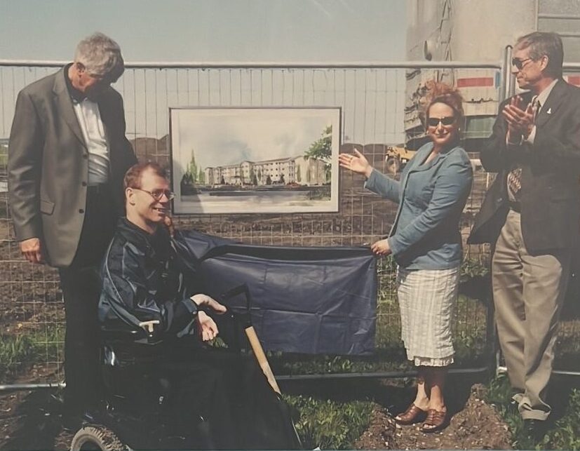 Celebratory groundbreaking — Travis McNally unveils the building sign while supporters applaud