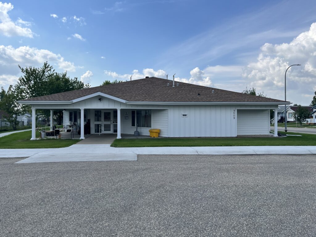 Single-storey residential building with covered entrance and front walkway and paved parking driveway