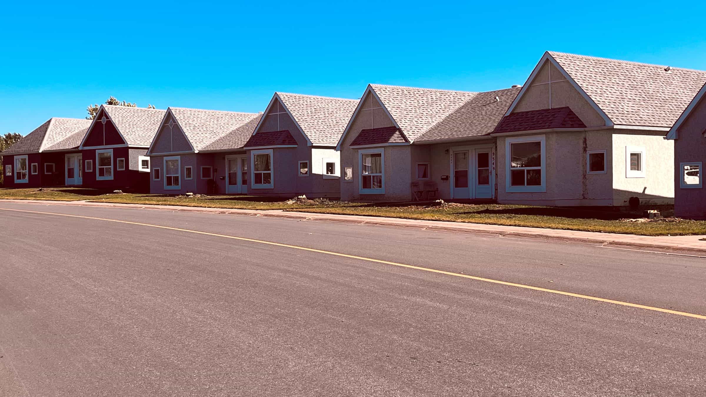 A row of GPRS single-storey barrier-free homes in Grande Prairie under a clear blue sky, each with its own front entrance